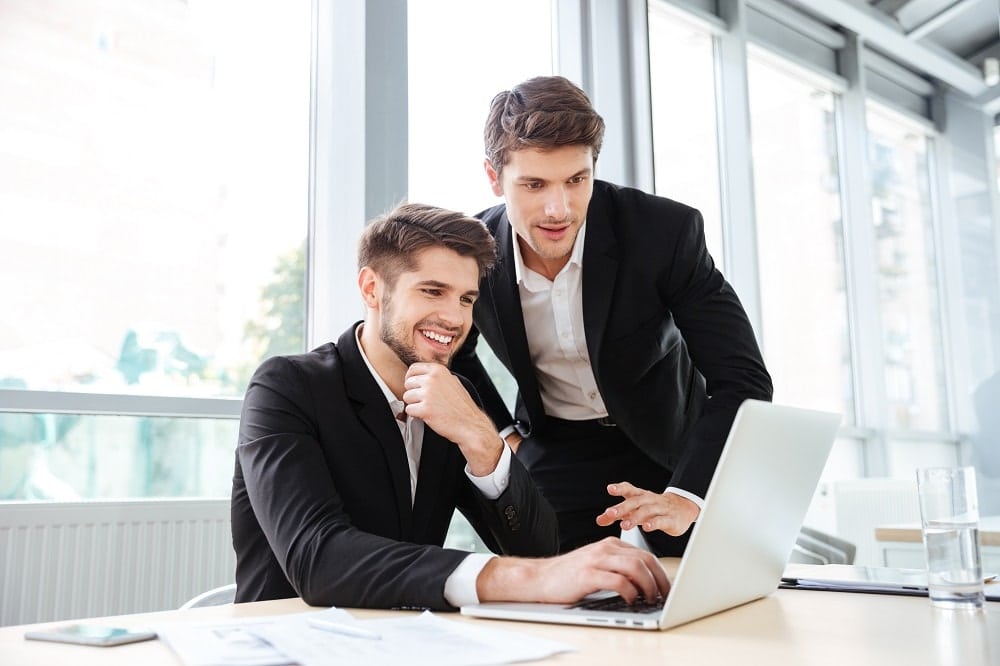 two-cheerful-young-businessmen-using-laptop